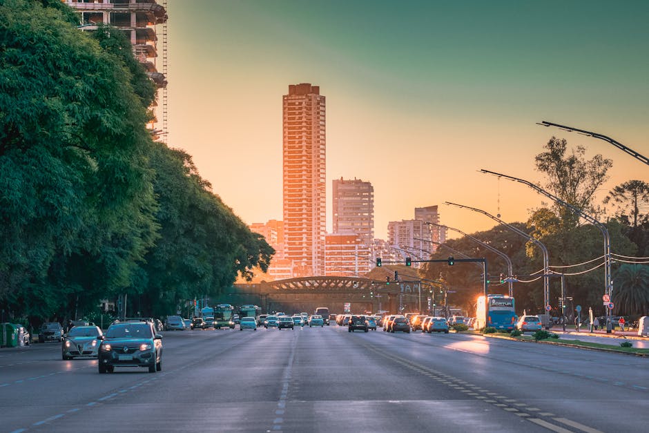 pexels photo 13545391 13545391 Bustling city street with traffic and skyscrapers at sunset, capturing urban life and architecture.